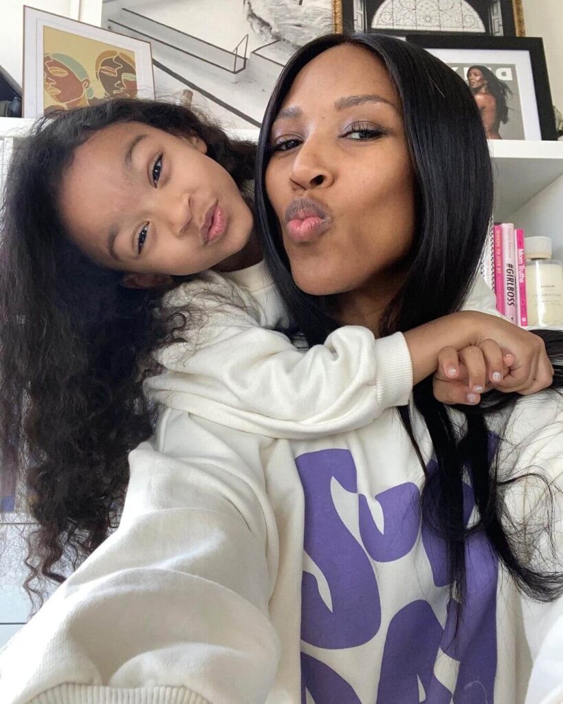 An adult and a child with long hair pose for a selfie